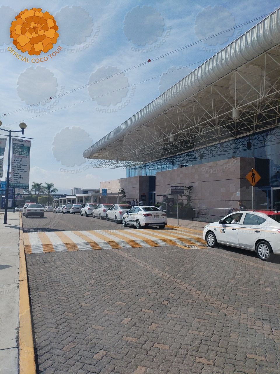 A line of white taxis with orange stripes waiting under the canopy outside Morelia bus station